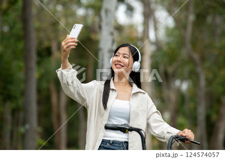 A woman looking happily at her notebook as she figure something out while sitting on park sidewalk 124574057