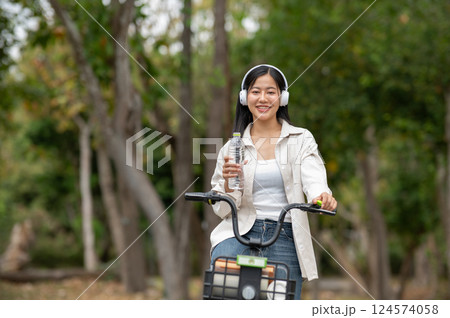 A woman looking happily at her notebook as she figure something out while sitting on park sidewalk 124574058