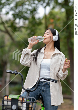 A woman looking happily at her notebook as she figure something out while sitting on park sidewalk A woman looking happily at her notebook as she figure something out while sitting on park sidewalk 124574059