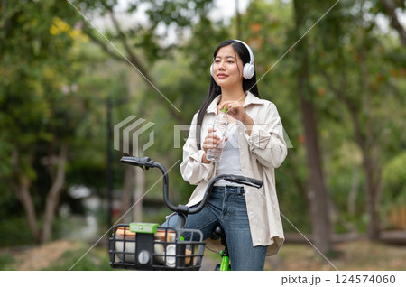 A woman looking happily at her notebook as she figure something out while sitting on park sidewalk 124574060