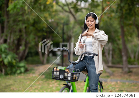 A woman looking happily at her notebook as she figure something out while sitting on park sidewalk 124574061