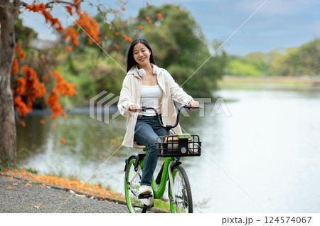 A woman looking happily at her notebook as she figure something out while sitting on park sidewalk A woman looking happily at her notebook as she figure something out while sitting on park sidewalk 124574067