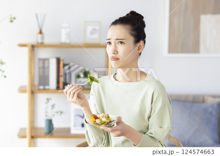 サラダを食べるのに飽きてしまった女性 124574663