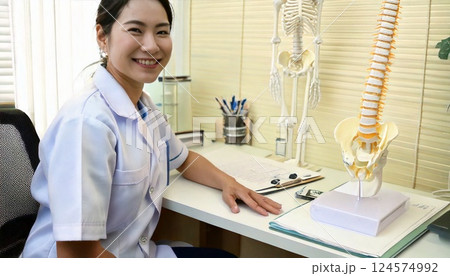 机に座りこちらを振り返る整体師　 124574992