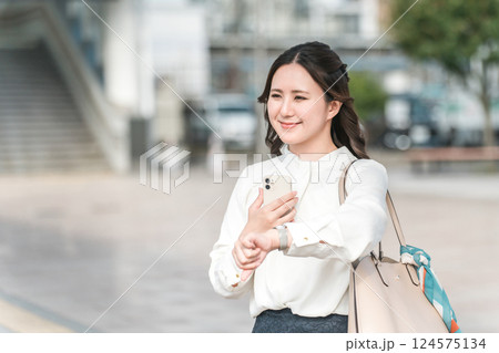 出張に行くため駅でバス・タクシーを待つビジネスウーマン（バス停・タクシー乗り場・ロータリー） 124575134