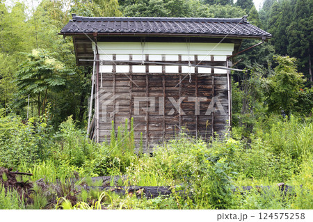 田舎の街道沿いからの風景 夏草が覆う古民家の蔵 124575258