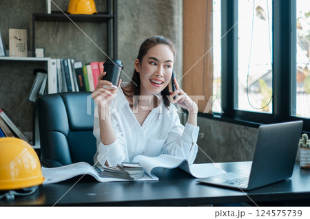 Professional woman multitasking in a contemporary office setting, engaging in a phone call and holding a coffee cup. Professional woman multitasking in a contemporary office setting, engaging in a phone call and holding a coffee cup. 124575739