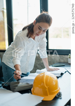 Professional woman architect examining plans in a contemporary office setting, highlighting construction and design concepts. Professional woman architect examining plans in a contemporary office setting, highlighting construction and design concepts. 124575740