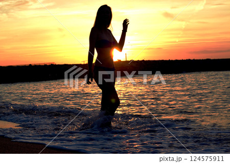 Silhouette of a woman at sunset by the water in Spain Silhouette of a woman at sunset by the water in Spain 124575911