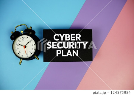 Cybersecurity Plan text with alarm clock on paper card on blue, purple, pink geometric background 124575984
