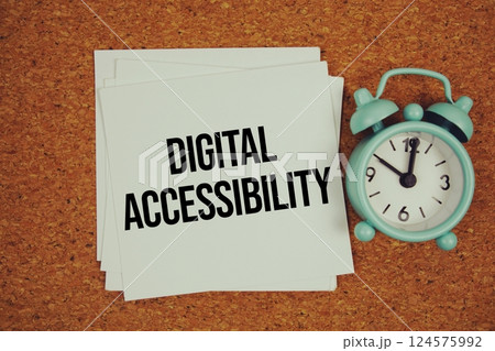 Digital Accessibility text on sticky note with alarm clock on cork paper background 124575992
