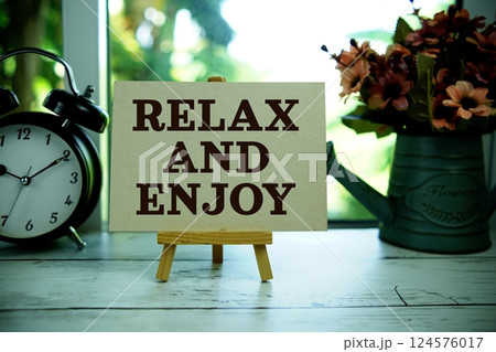 Relax and Enjoy text  motivational and inspiration quote with alarm clock on wooden background 124576017