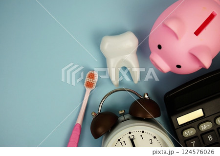Dental Treatment Costs with toothbrush, calculator, piggy bank and white tooth model top view on blue background 124576026