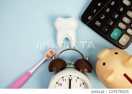 Dental Treatment Costs with toothbrush, calculator, piggy bank and white tooth model top view on blue background 124576028