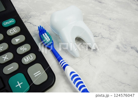 Toothbrush and Tooth with calculator top view on marble background, Dental money and dentist treatment costs Toothbrush and Tooth with calculator top view on marble background, Dental money and dentist treatment costs 124576047