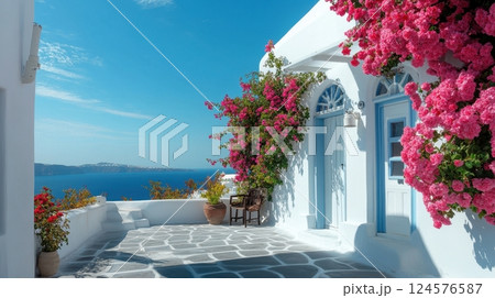 whitewashed house with blue accents, adorned with vibrant pink bougainvillea, overlooking the serene blue sea 124576587