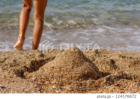 Sand castle on sea beach and child legs 124576672