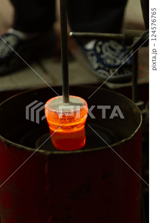 A mesmerizing close-up of a skilled artisan blowing molten glass into shape A mesmerizing close-up of a skilled artisan blowing molten glass into shape 124576765