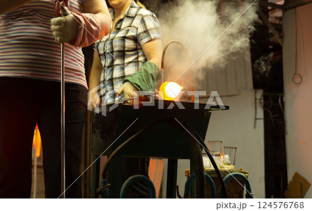 A glass blower is working on the manufacture of glass vases and glasses. A glass blower is working on the manufacture of glass vases and glasses. 124576768