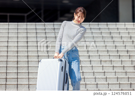 重いスーツケースを持って階段を降りる女性 124576851