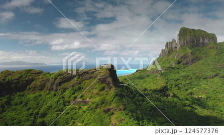 Mountain Otemanu dominates over green topical jungle landscape of Bora Bora volcanic island in French Polynesia, turquoise lagoon and coral reefs. Aerial drone view, bird fly over wild nature scene Mountain Otemanu dominates over green topical jungle landscape of Bora Bora volcanic island in French Polynesia, turquoise lagoon and coral reefs. Aerial drone view, bird fly over wild nature scene 124577376