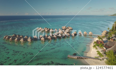 Aerial view idyllic scene of overwater bungalows perched above vibrant turquoise lagoon, tropical island getaway. Popular tourist destination. Remote wild nature paradise, exotic summer travel Aerial view idyllic scene of overwater bungalows perched above vibrant turquoise lagoon, tropical island getaway. Popular tourist destination. Remote wild nature paradise, exotic summer travel 124577401