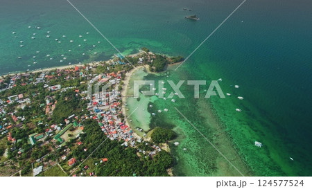 Stunning aerial view of Malapascua Island in the Philippines, featuring vibrant coral reefs, crystal-clear turquoise waters, traditional outrigger boats, and coastal houses 124577524