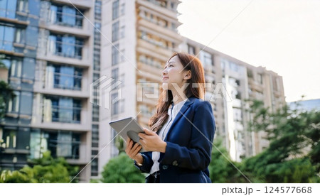 集合住宅の前に立ち建物を見回す不動産業の女性 124577668