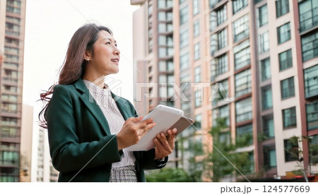 集合住宅の前に立ち建物を見回す不動産業の女性 124577669