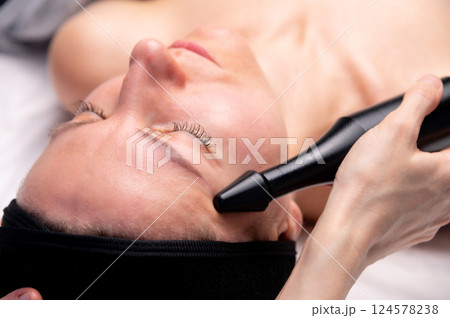 Ultrasonic facial treatment ultrasound face machine. Woman receiving electric lift massage spa salon. Electronic stimulation female muscles. Improvement of skin condition 124578238