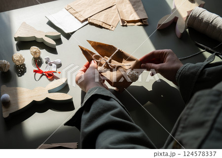 Step by step instruction of making handmade Easter gift bag rabbit bunny shaped sustainable materials decorations from craft paper. Female hands creating craft homemade present. Easter celebration Step by step instruction of making handmade Easter gift bag rabbit bunny shaped sustainable materials decorations from craft paper. Female hands creating craft homemade present. Easter celebration 124578337