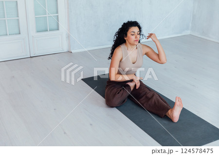 Brunette woman doing gymnastics yoga asana on the floor Brunette woman doing gymnastics yoga asana on the floor 124578475
