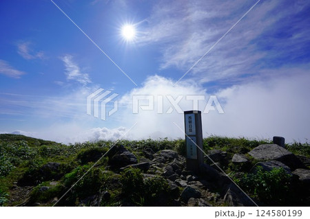 西朝日岳の山頂標識と太陽 124580199