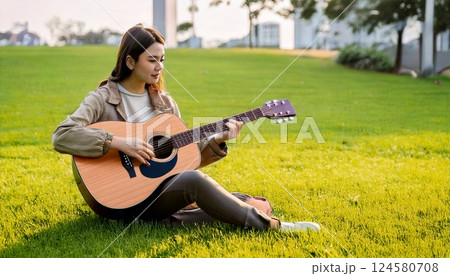 キャンパスの芝生でギターを演奏する女性 キャンパスの芝生でギターを演奏する女性 124580708