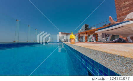 Tourist relaxing by rooftop pool with refreshing drink on summer day Tourist relaxing by rooftop pool with refreshing drink on summer day 124581077