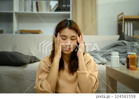 Young woman suffering from headache sitting on the floor with hands on her temples Young woman suffering from headache sitting on the floor with hands on her temples 124581559