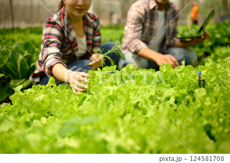 Farmers discussing farming progress while using a digital tablet in greenhouse 124581708