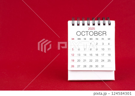White desk calendar for October 2025 on red background. 124584301