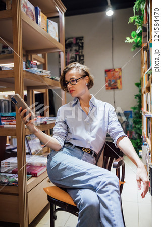 Woman with glasses among shelves with books in university library Woman with glasses among shelves with books in university library 124584470