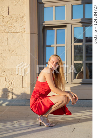 Beautiful woman in a red dress near an old building Beautiful woman in a red dress near an old building 124584727
