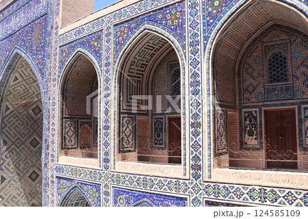 Famous landmark - Ulugh Beg Madrasah on Registan square, Samarkand, Uzbekistan. Arches with tile ornament in the courtyard of Ulugh Beg Madrasa. Text on the wall is a quote from the Quran 124585109