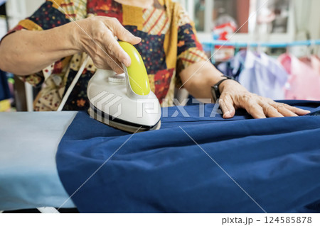 Senior citizens ironing student skirt and clothing in a house. Senior citizens ironing student skirt and clothing in a house. 124585878