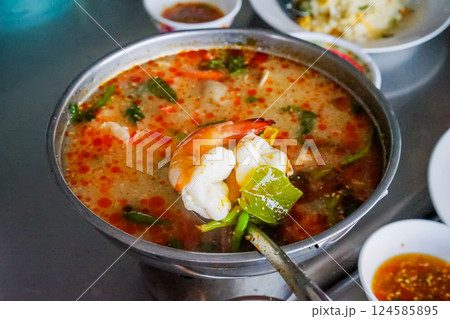 Tom Yum Kung Nam Khon or Thai creamy hot and spicy herbal soup with shrimp served in Thai style hot pot at the famous local restaurant. Tom Yum Kung Nam Khon or Thai creamy hot and spicy herbal soup with shrimp served in Thai style hot pot at the famous local restaurant. 124585895