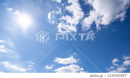 The bright sun with an overlay shines through the earth atmosphere. Beautiful blue sky with clouds and the sun in the midday. The bright sun with an overlay shines through the earth atmosphere. Beautiful blue sky with clouds and the sun in the midday. 124585897