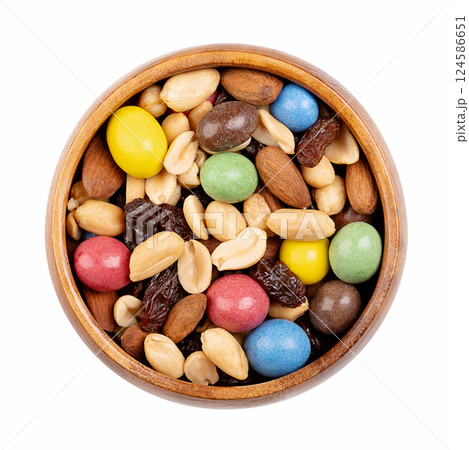 Rainbow trail mix in a wooden bowl. Snack mix of candy coated milk chocolate peanuts, roasted peanuts, raisins, and roasted almonds. Combination of sweets, dried fruits, and nuts. Isolated from above. 124586651