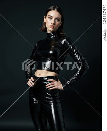 Futuristic fashion portrait of woman in sleek black faux leather outfit against minimalistic dark background 124587474