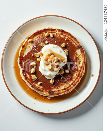 Gourmet pancake breakfast with syrup, whipped cream, and nuts for a cozy brunch setting 124587480