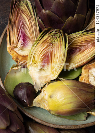 Plate full of cut purple raw artichokes closeup. Fresh italian vegetables from farmers market 124587973