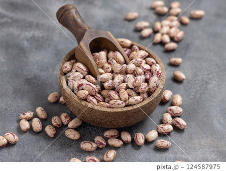 Wooden bowl full of dried pinto beans with scoop on gray closeup. Traditional Latin American legumes Wooden bowl full of dried pinto beans with scoop on gray closeup. Traditional Latin American legumes 124587975