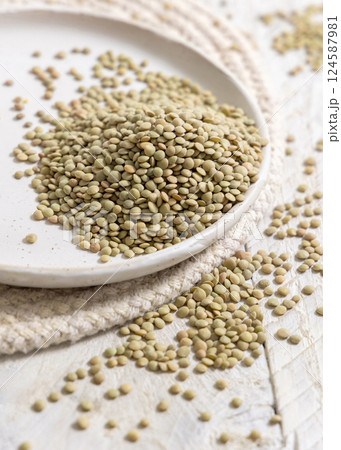 Plate full of dried raw green lentils on white table closeup. Traditional mediterranean legume 124587981